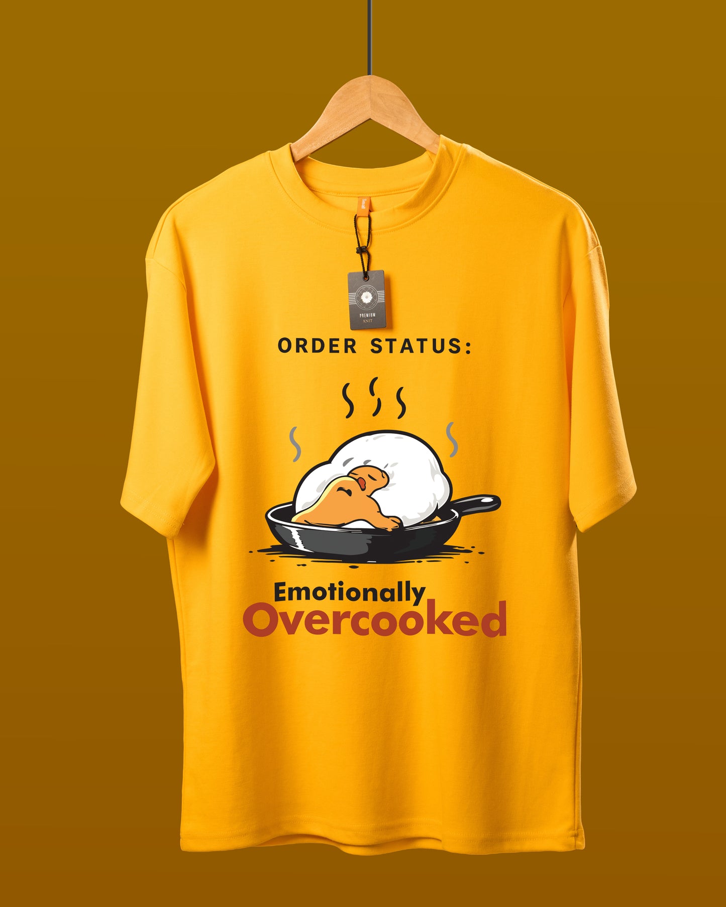 DUMM Emotionally Overcooked oversized t-shirt in mustard yellow on wooden hanger